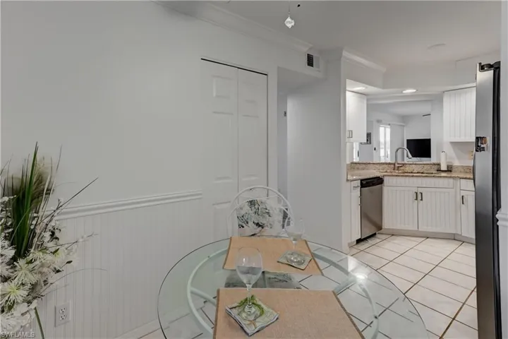 Kitchen with breakfast nook area featuring white beadboard cabinets and wainscoting, granite countertops, and stainless steel appliances.