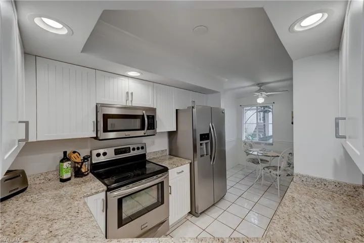 Kitchen featuring white beadboard cabinetry, stainless steel appliances, granite counters, recessed lighting and breakfast nook area.