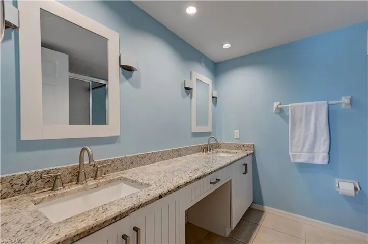 Primary bathroom with dual vanities, beadboard cabinets, granite countertop and shower (not shown).
