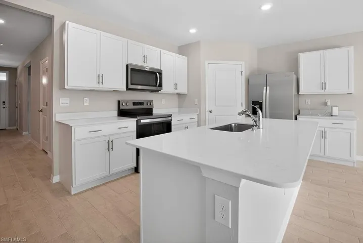 Kitchen with appliances with stainless steel finishes, white cabinetry, a center island with sink, recessed lighting, and light wood-style flooring