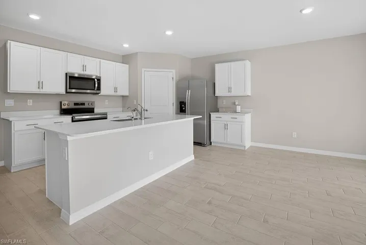 Kitchen featuring light countertops, white cabinetry, stainless steel appliances, and recessed lighting