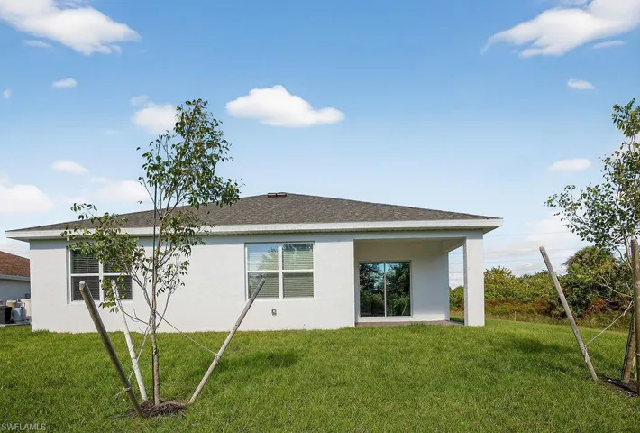 Back of house with a yard, stucco siding, and a patio area