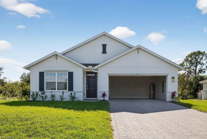 Single story home with stucco siding, decorative driveway, a front yard, and an attached garage
