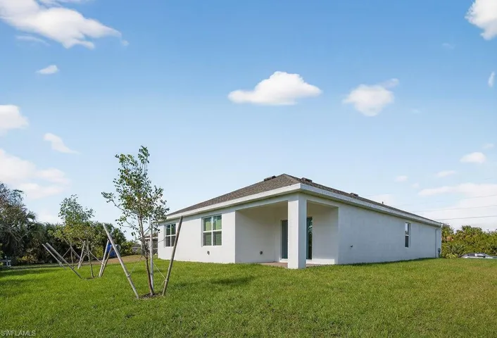 Rear view of house featuring a lawn, a patio area, and stucco siding