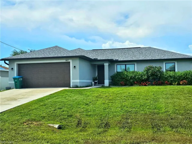 View of front of home with a garage and a front lawn
