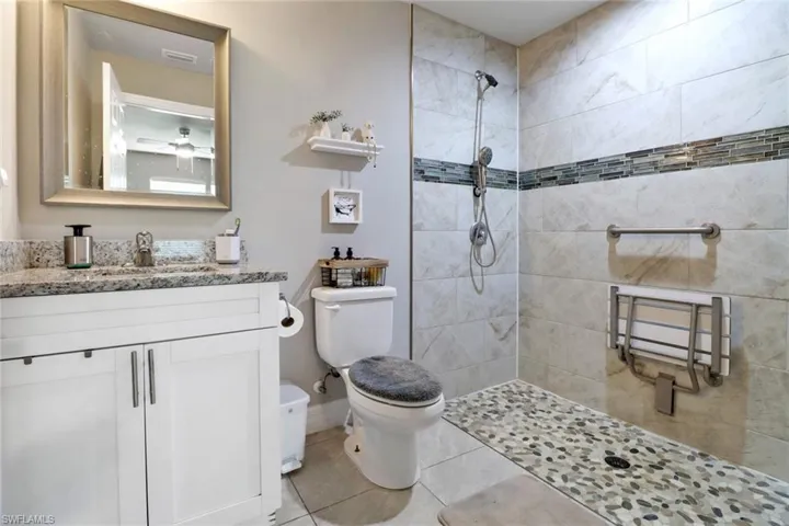 Bathroom featuring radiator heating unit, tile patterned flooring, a tile shower, toilet, and vanity