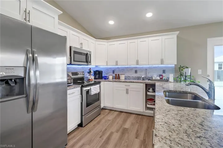 Kitchen featuring white cabinetry, stainless steel appliances, light wood-type flooring, sink, and backsplash