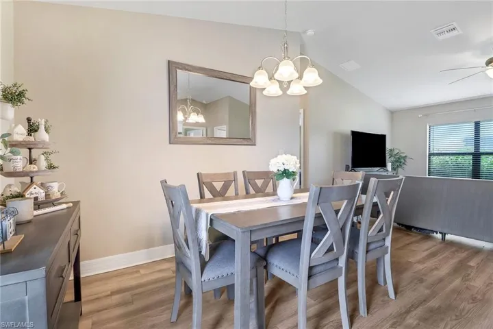 Dining area featuring ceiling fan with notable chandelier, lofted ceiling, and hardwood / wood-style floors