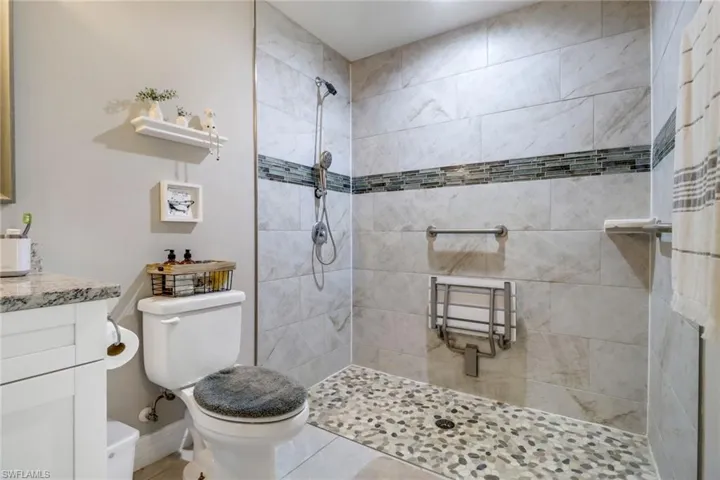 Bathroom featuring vanity, tiled shower, toilet, and tile patterned floors