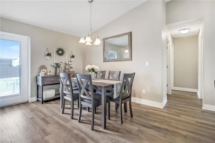 Dining area featuring an inviting chandelier, hardwood / wood-style flooring, and vaulted ceiling