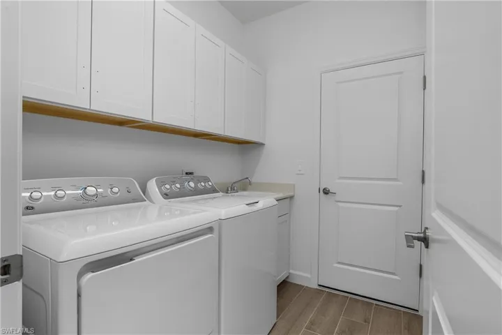 Laundry room features added cabinetry for convenient storage.