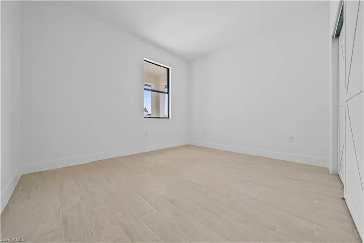 Spare room featuring light wood-type flooring and vaulted ceiling