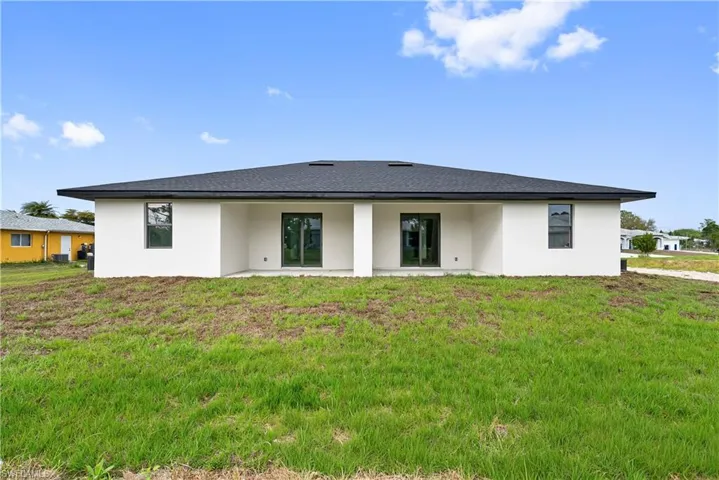 Rear view of property with stucco siding, a patio, and a lawn