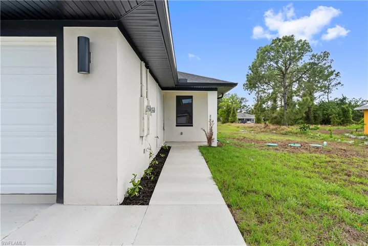 Property entrance with stucco siding, a lawn, and a garage