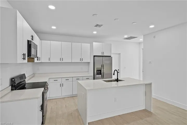 Kitchen with stainless steel appliances, light stone countertops, white cabinetry, and recessed lighting