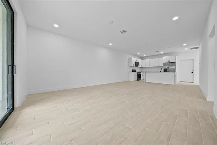 Unfurnished living room featuring arched walkways, recessed lighting, and wood finish floors