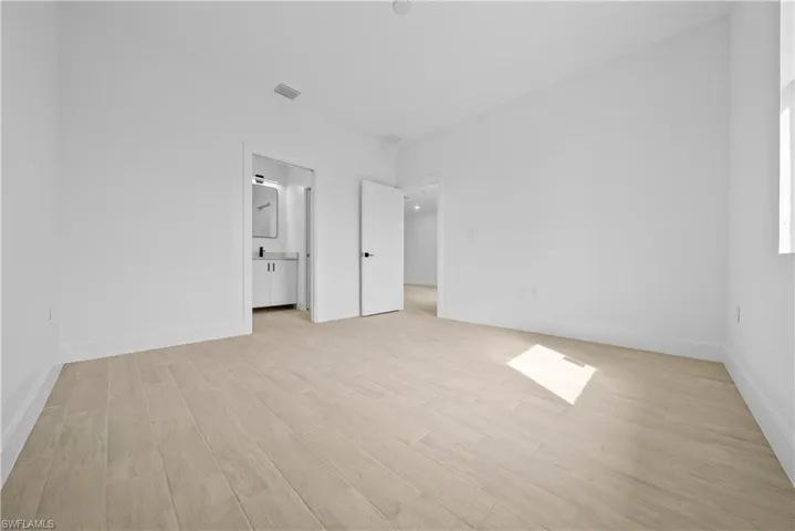 Unfurnished bedroom featuring light wood-style floors and ensuite bathroom