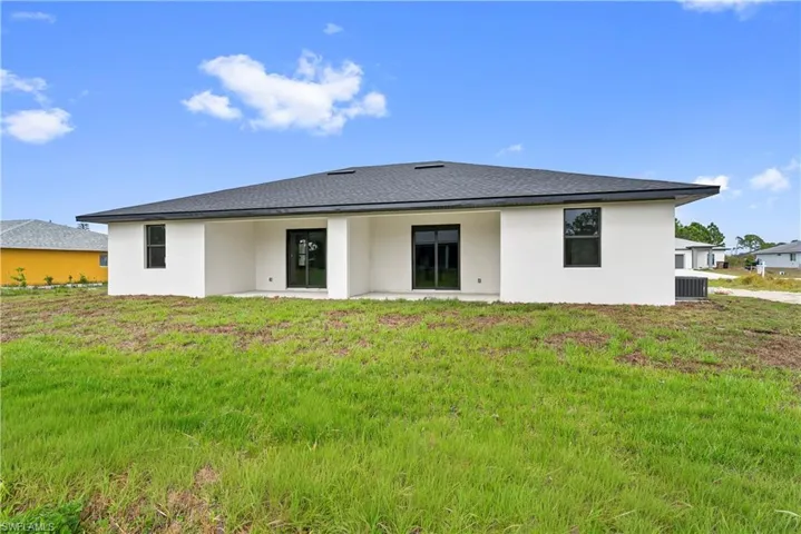 Back of property featuring stucco siding, a patio, and a yard