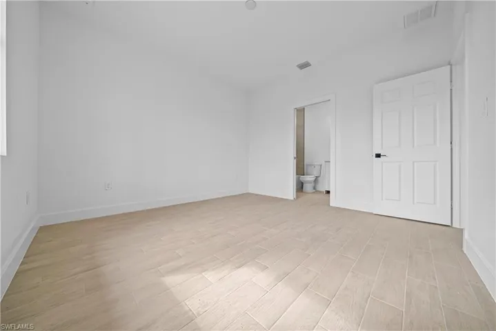 Unfurnished bedroom featuring wood tiled floors and connected bathroom