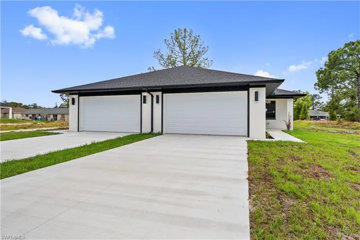 View of front facade featuring concrete driveway, roof with shingles, stucco siding, a front yard, and an attached garage