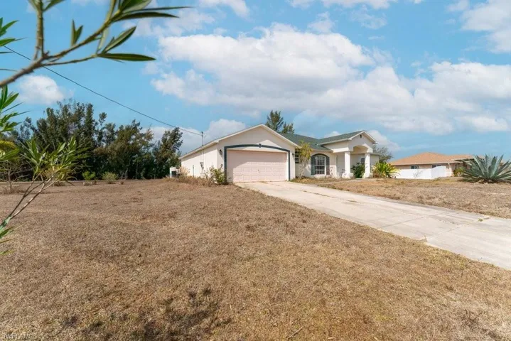 Ranch-style home featuring stucco siding, driveway, and a garage