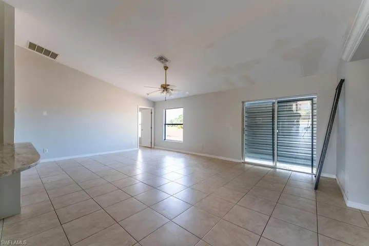 Unfurnished room featuring lofted ceiling, light tile patterned flooring, and a ceiling fan