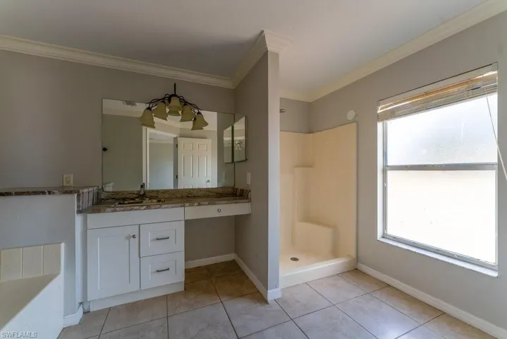 Bathroom featuring a shower stall, vanity, crown molding, a bath, and light tile patterned floors