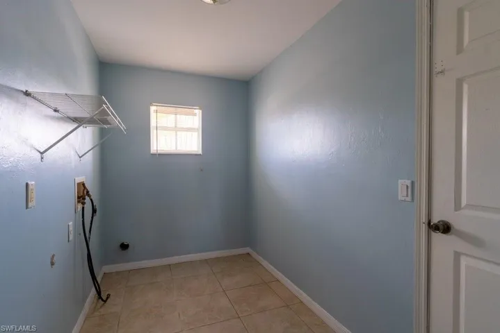 Laundry area with washer hookup and light tile patterned flooring