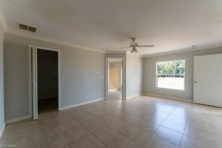 Unfurnished room with crown molding, a ceiling fan, and light tile patterned floors