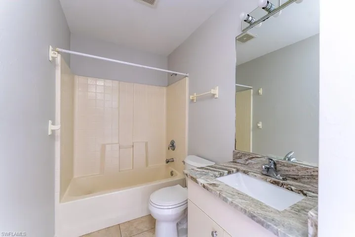 Bathroom featuring vanity, shower / bath combination, and light tile patterned flooring