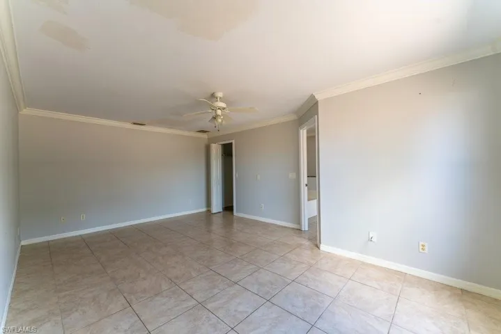 Spare room featuring crown molding, ceiling fan, and light tile patterned floors
