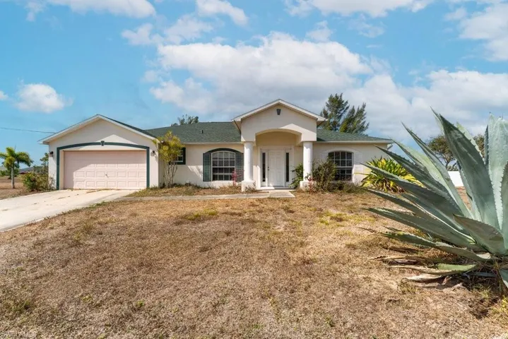 Ranch-style home with an attached garage, concrete driveway, stucco siding, and a front lawn