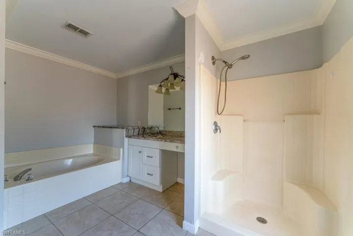 Bathroom with crown molding, vanity, a stall shower, a garden tub, and light tile patterned floors