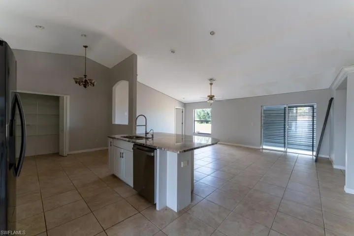 Kitchen featuring black refrigerator with ice dispenser, white cabinetry, a kitchen island with sink, stainless steel dishwasher, and open floor plan