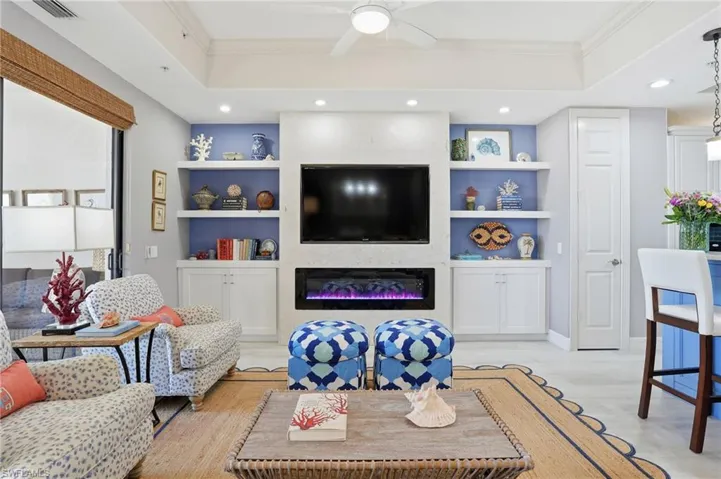 Living area featuring ornamental molding, ceiling fan, light wood-style floors, a glass covered fireplace, and recessed lighting