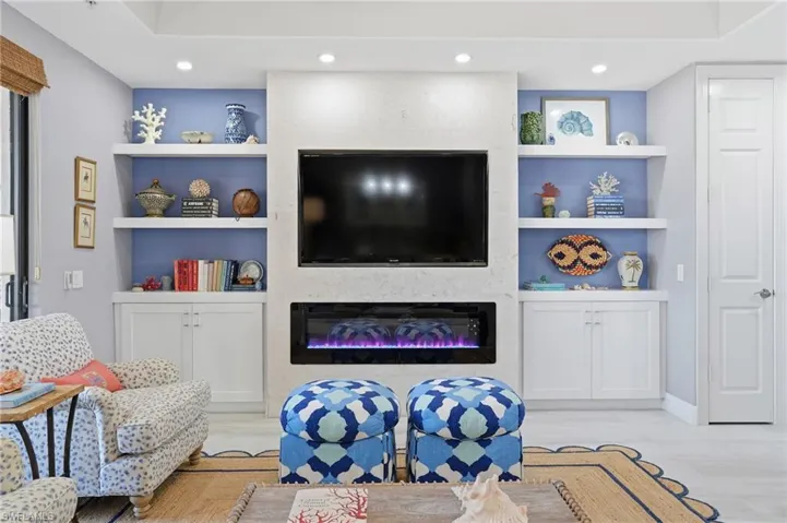 Living room featuring built in features, a glass covered fireplace, light wood finished floors, and recessed lighting