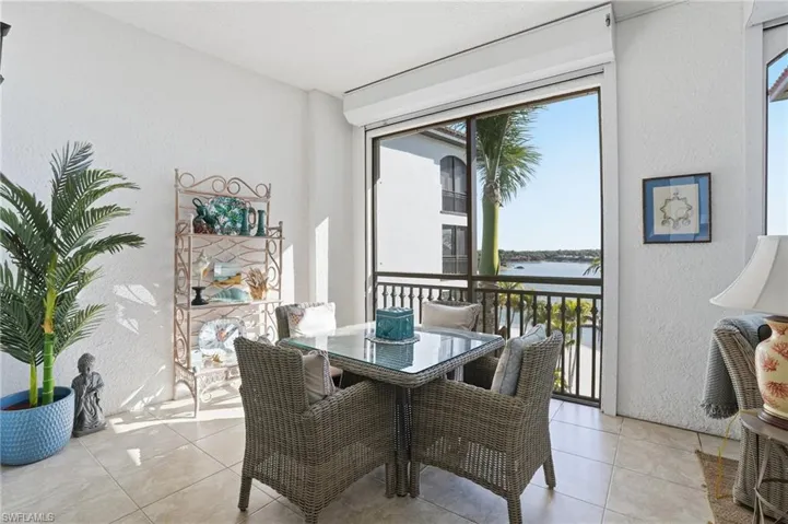 Dining room with a textured wall, a water view, and light tile patterned floors