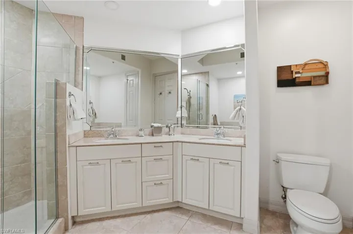Bathroom featuring a stall shower, double vanity, and light tile patterned flooring