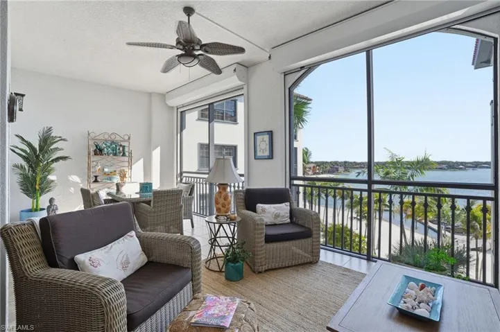 Sunroom / solarium featuring ceiling fan, a water view, and a balcony