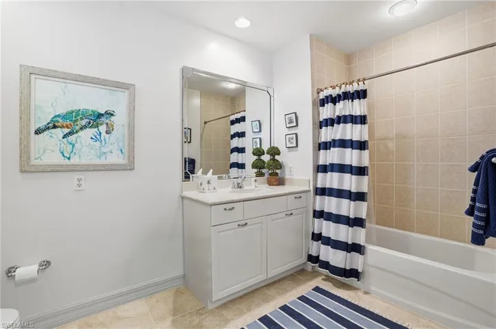 Bathroom with vanity, shower / bath combination with curtain, light tile patterned floors, and recessed lighting