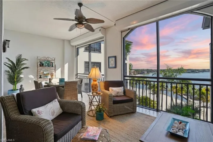 Sunroom / solarium featuring a ceiling fan, a balcony, a water view, and outdoor dining space