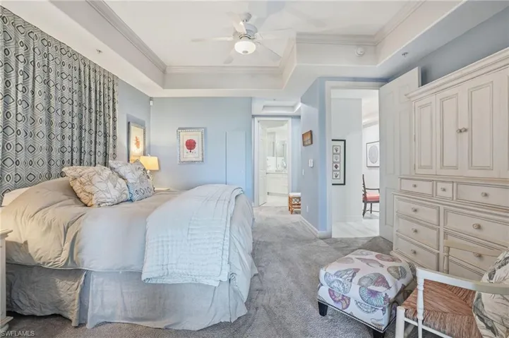 Carpeted bedroom featuring ornamental molding, a ceiling fan, and a tray ceiling