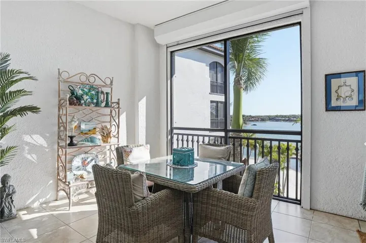 Dining room with a textured wall, a water view, and light tile patterned floors
