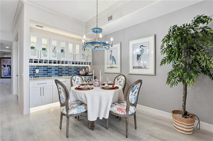 Dining room with light wood-type flooring, crown molding, and hanging lights