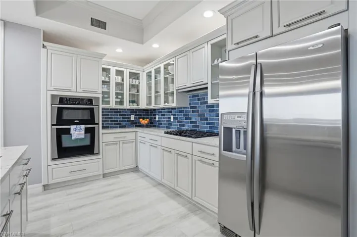 Kitchen featuring crown molding, stainless steel appliances, glass insert cabinets, recessed lighting, and tasteful backsplash