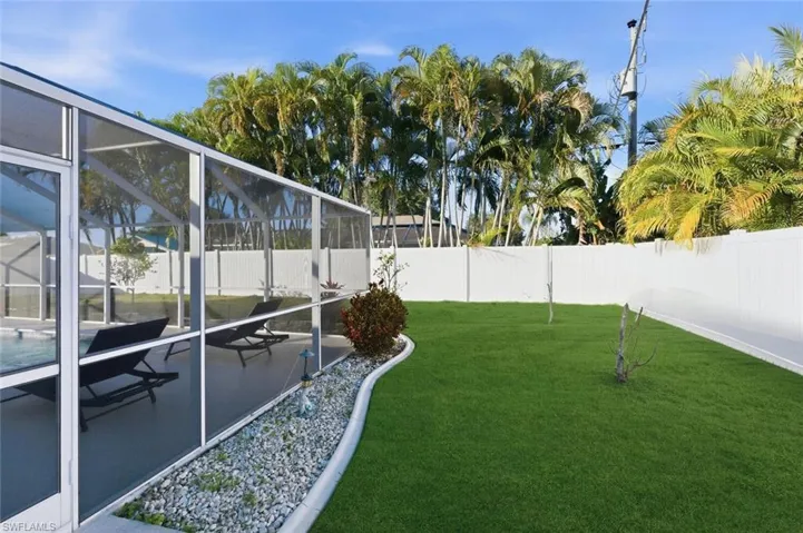 Fenced backyard featuring a sunroom, glass enclosure, and a patio area