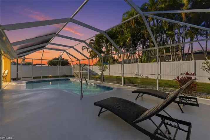 Pool at dusk with a sunroom, a fenced backyard, a lanai, and a patio
