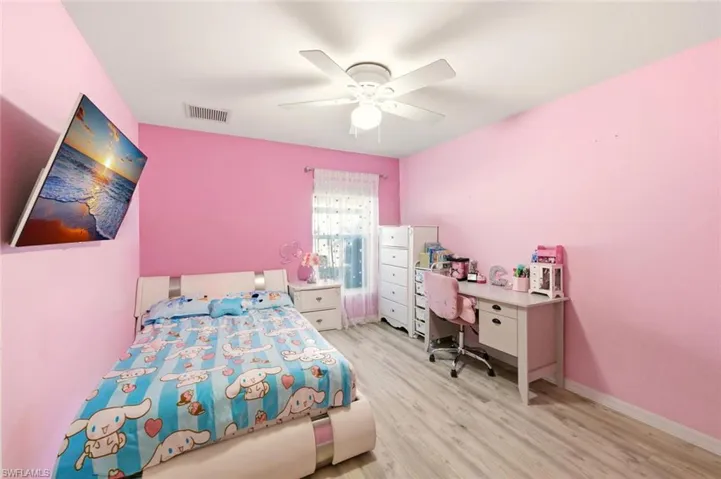 Bedroom with ceiling fan, light wood-style flooring, and an office area