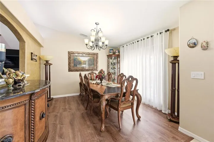 Dining space with dark wood-style flooring, a chandelier, and lofted ceiling
