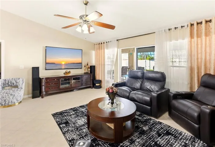 Living room featuring vaulted ceiling, light tile patterned floors, and ceiling fan